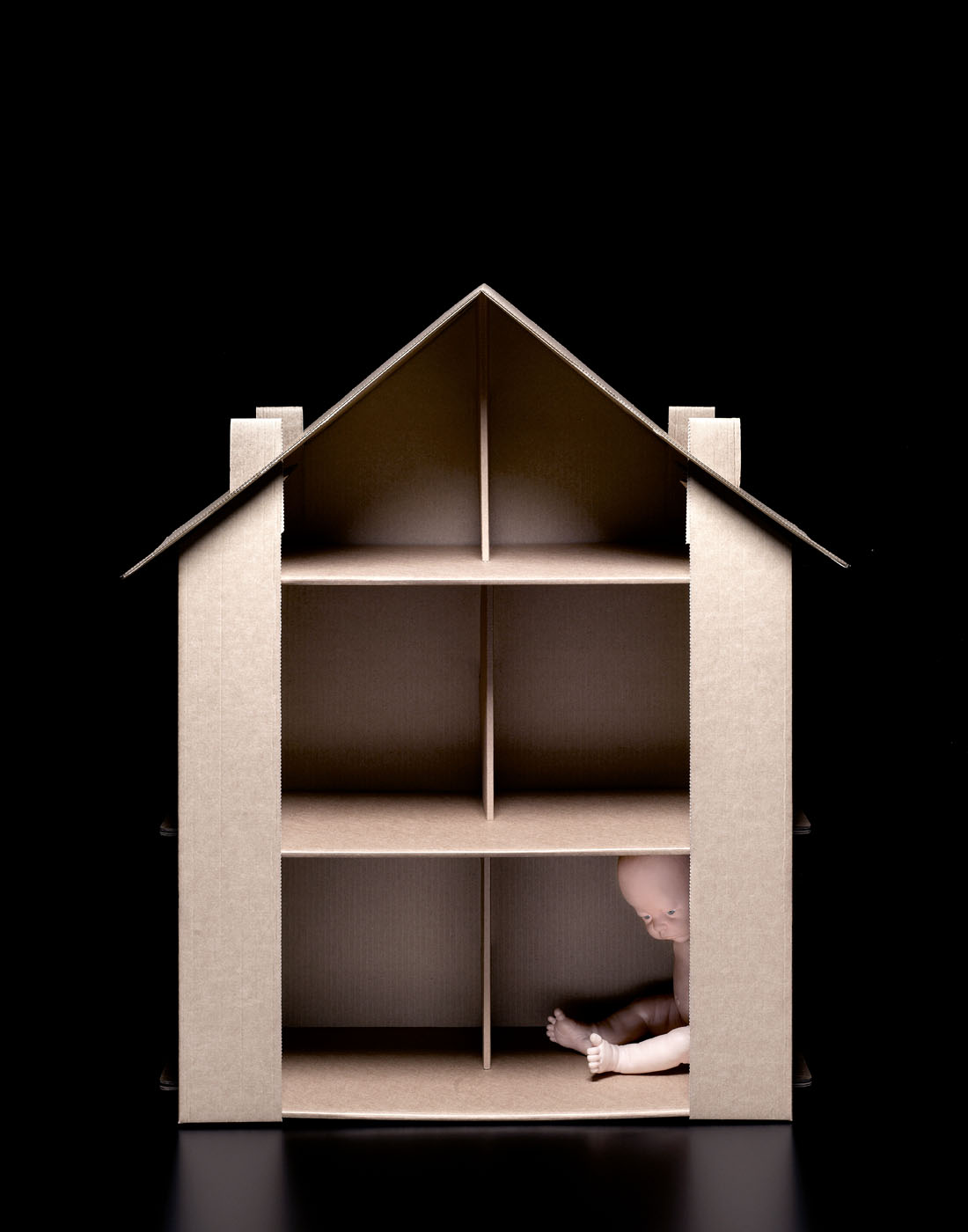 Sad baby doll in recycled paper house by Alexander Kent London based still life and product photographer.
