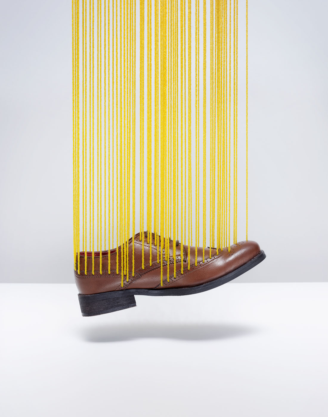 Suspended brogue shoe with yellow wool by Alexander Kent London based still life and product photographer.