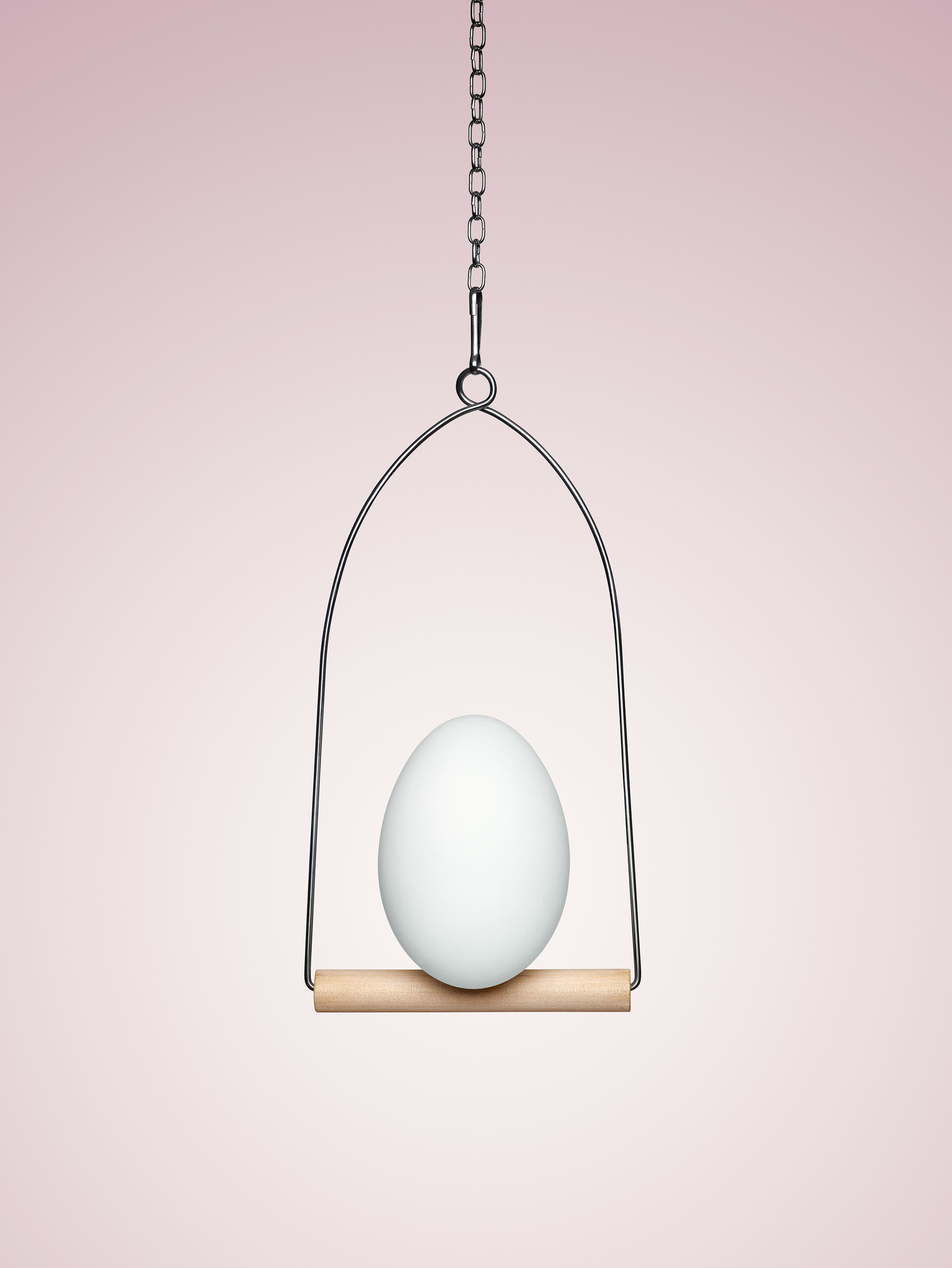 Egg perching on swing in pink room by Alexander Kent London based photographer.