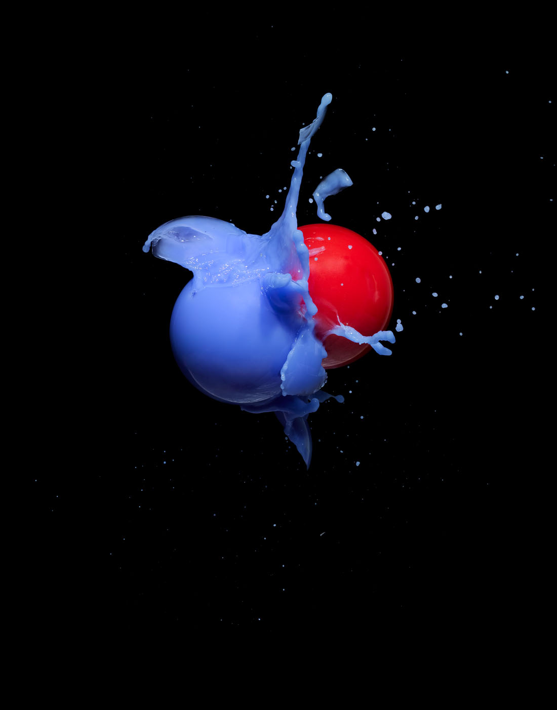 Red and blue balls smashing together by Alexander Kent London based still life and product photographer.